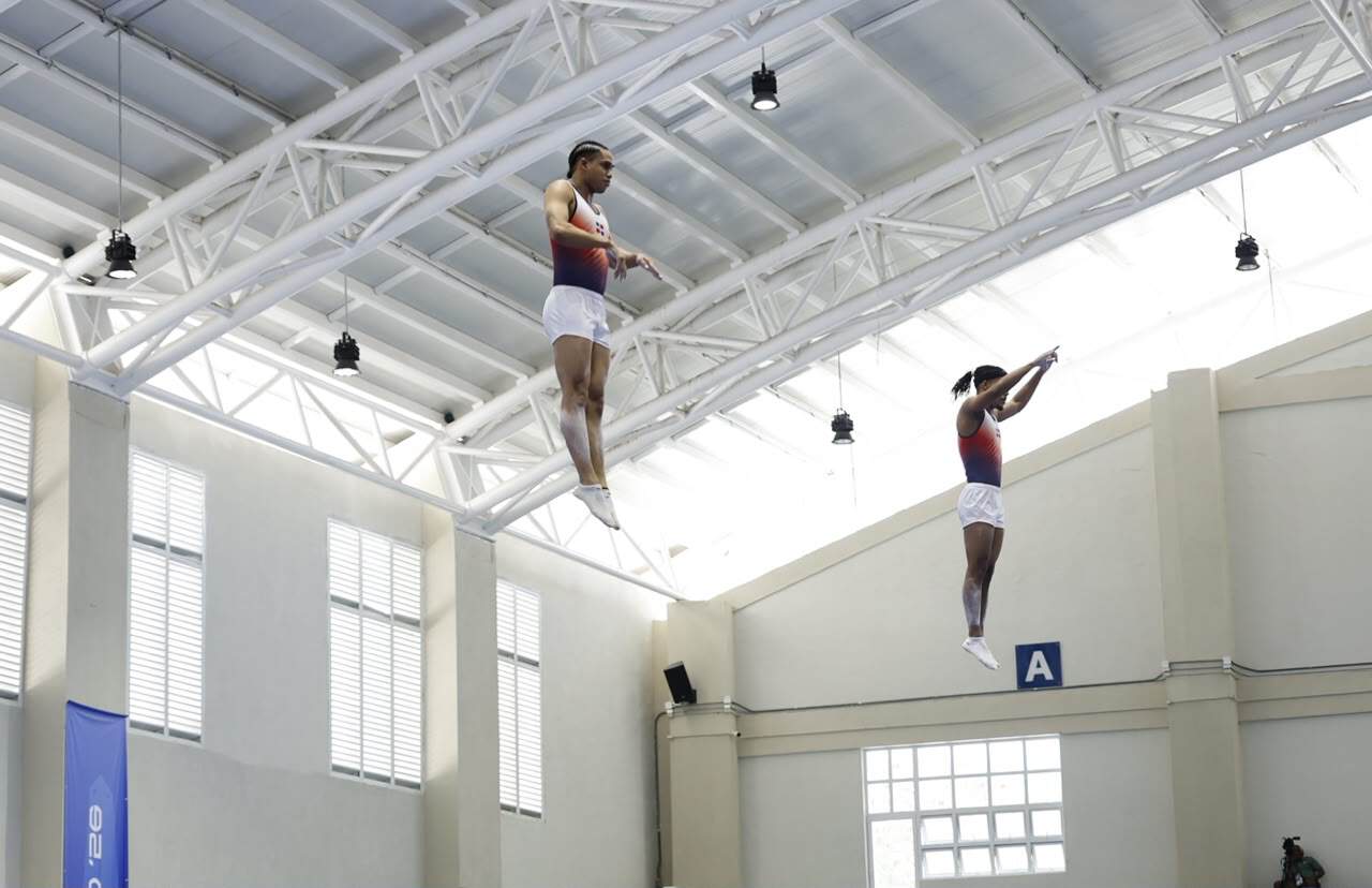 Los dominicanos Emil De La Rosa y Junior Zapata realizan acrobacias aéreas durante la final de gimnasia trampolín de los Juegos Centroamericanos y del Caribe 2026.